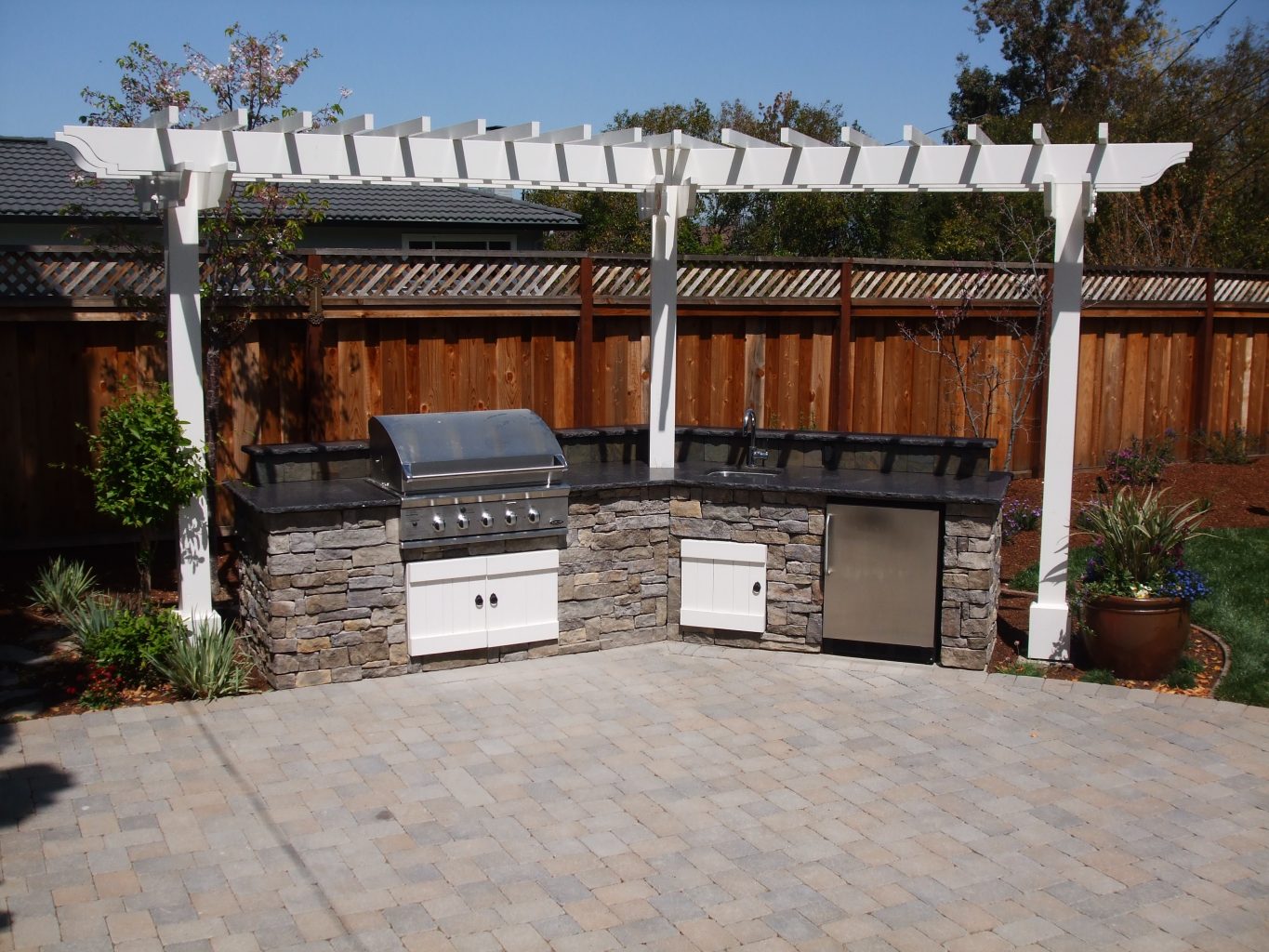 custom bbq with stone veneer with small arbor and paver patio