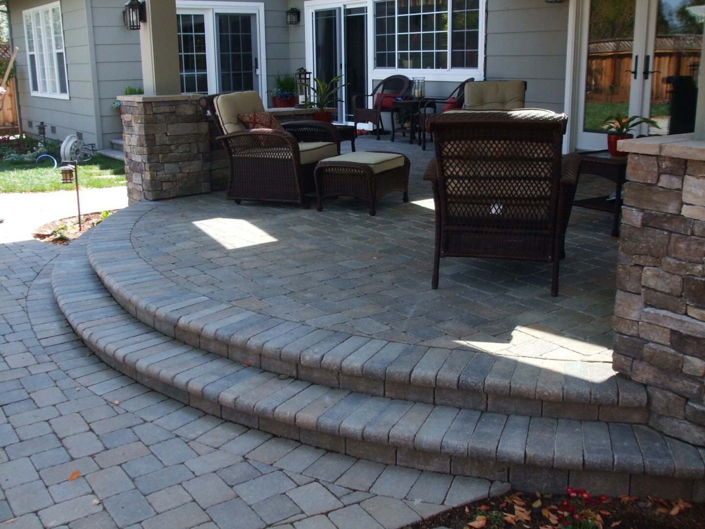 Timeless addition of a covered paver patio with natural stone veneer columns